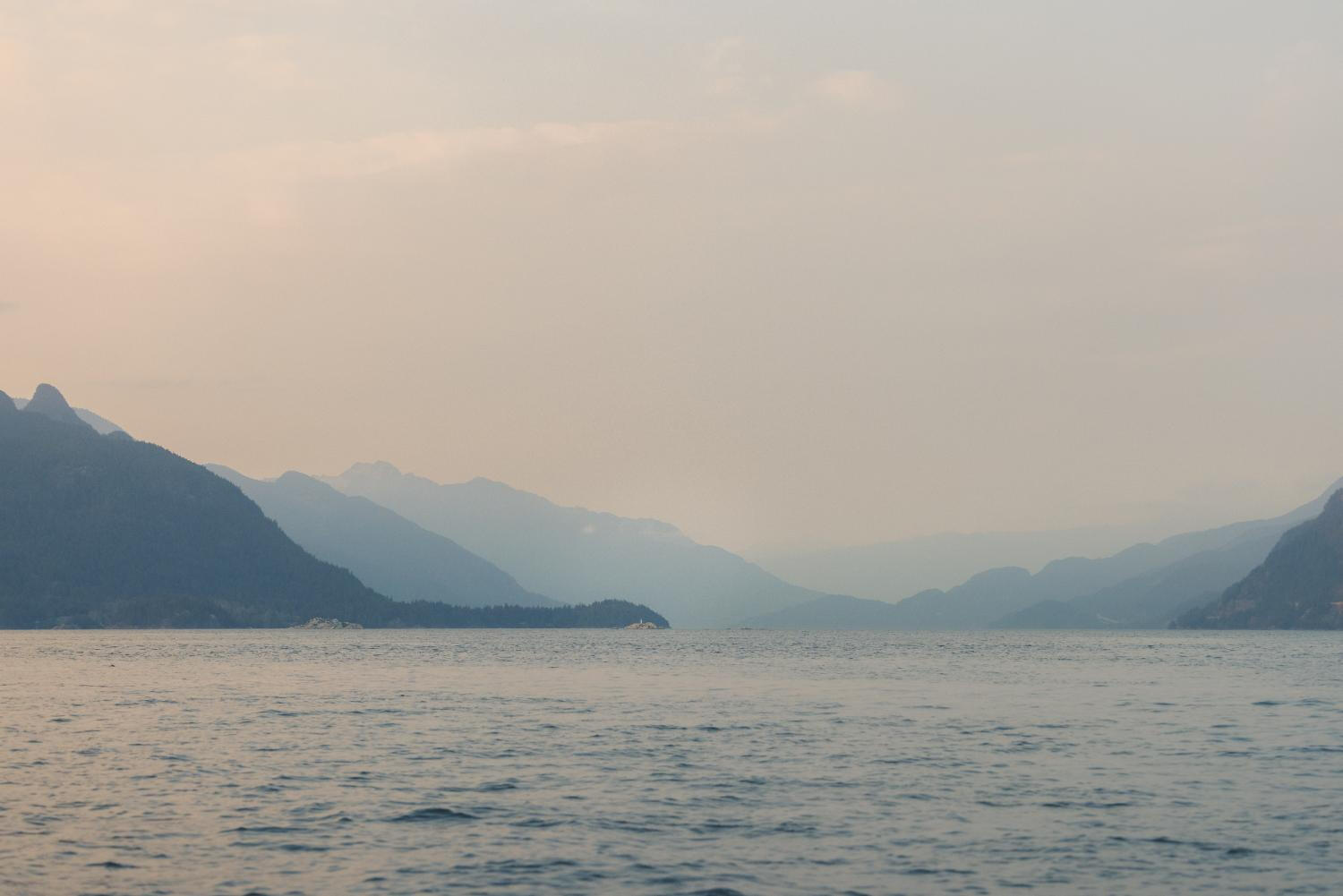 A serene scene of a boat navigating the ocean, framed by towering mountains in the distance. A serene scene of a boat navigating the ocean, framed by towering mountains in the distance.