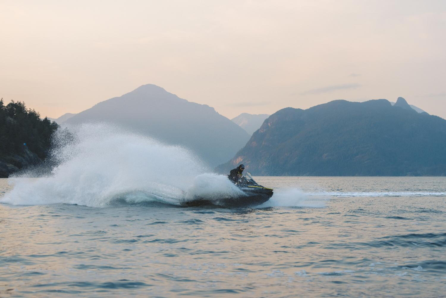A rider navigates a jet ski through the vibrant ocean, creating splashes against the serene water backdrop.