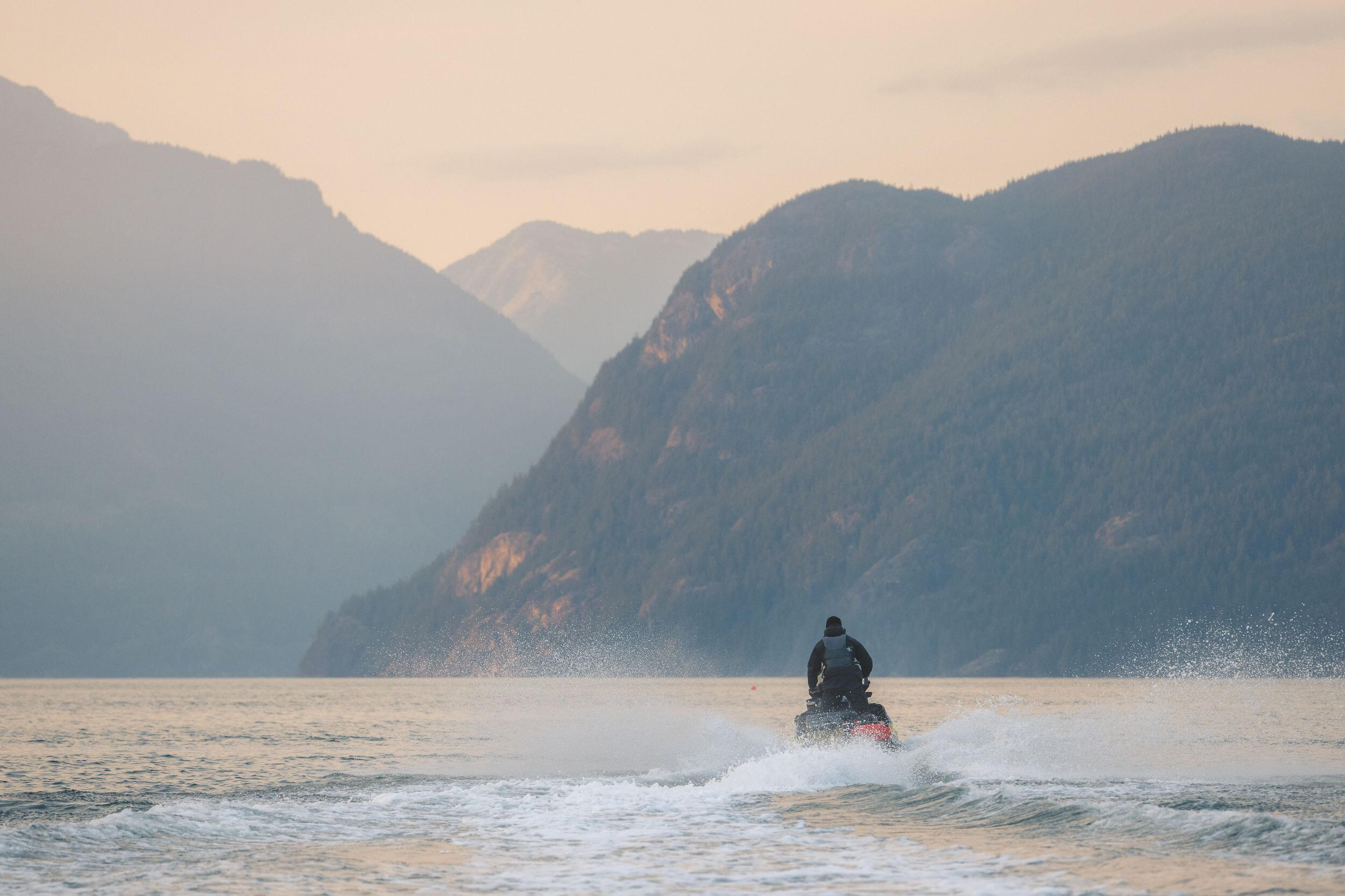 An individual navigates a jet ski through the vibrant ocean, creating splashes against the serene water backdrop. An individual navigates a jet ski through the vibrant ocean, creating splashes against the serene water backdrop.